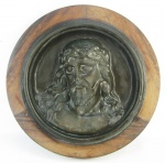 Placa circular em bronze, com trabalhos em alto relevo representando "Busto de Cristo". Moldura em jacarandá. Diam. com moldura 44cm.