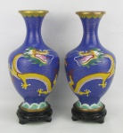 Par de vasos em cloisoné oriental no tom azul, decorados com dragões em policromia. Acompanha peanhas em madeira entalhada, com detalhes vazados. Um com imperceptível mossa na parte bojuda. Alt. total 29,5cm.