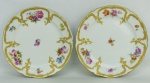 KPM Berlim - Par de pratos em porcelana alemã, com marca da manufatura no verso, decorados com pintura floral em policromia e detalhes dourados em relevo. Minúsculos desgastes no dourado. Diam. 18,5cm.