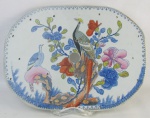 Descanso de mesa em porcelana inglesa, com marca da manufatura Patent Ironstone China no verso, decorada com paisagem de pássaros, flores e folhagens em policromia. Pequenos desgastes na policromia. Med. 35x26cm.