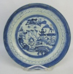 Prato de coleção em porcelana de Macau, do Séc. XIX, decorado em azul com pintura de paisagem com pagodes. Apresenta discreto e pequeno fio de cabelo no verso. Diam. 22cm.