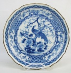 Antigo prato em porcelana oriental, decorado com pintura nos tons de azul com pássaro, flores e folhagens, marca da manufatura no verso. Diam. 22,5cm.