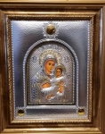 Ícone em metal prateado com representação de Nossa Senhora com Menino. Detalhes em dourado. Emoldurado. Med. com moldura 43x36cm.