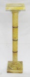 Coluna em ônix, tampo e base quadrados, corpo torneado com anéis em bronze. Apresenta pequenas perdas no tampo. Med. 99x25x25cm.