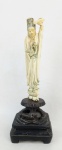 Escultura em marfim, representando "Dama no jardim", sobre flor de lotus. China, Período Revolucionário. Base em madeira. Alt. total 24,5cm.