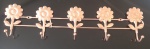Cabideiro em metal no tom cobre, com flores e cinco ganchos. Medidas: . 39x10 cm.