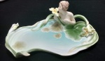 Porta cartão em porcelana policromada norte-americana da manufatura de unicórnio Studio ao gosto Art-Nouveau representando Mulher com folhas e flores  Medidas  8 x 23 x 16 cm. -A peça esta sendo leiloada para cobrir despesas de guarda e depósito, por não ter sido retirada por arrematante de leilões passados.