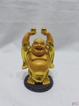 Escultura de Buda com os braços levantados em resina dourada. Medindo 12cm de altura.
