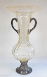 MURANO - Enorme ânfora / vaso em vidro italiano com folículos prateados, bojo canelado em vidro incolor, alças e base na cor roxo escuro. Med. 64 x 32 cm. Possui trincado embaixo do bojo.