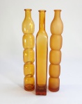 Três vasos no formato de garrafas compridas em vidro amarelo soprado e moldado. Possivelmente anos 60. Med. 32 cm.