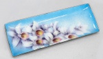 Covilhete em metal decorado com esmaltes policromados e desenhos de orquídeas. Med. 24 x 09 cm.