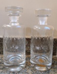 Par de garrafas em vidro/cristal com lapidação - mede 25 cm de altura e 9,5 cm de diâmetro (1 das tampas com encaixe irregular e pequeno bicado na borda).