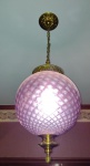 Lustre no formato de bola pendente com metal dourado e globo jateado com lapidação, na cor rubi - mede 80 cm de altura.