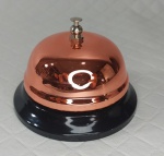 Sineta comercial de mesa/balcão de grande sonoridade manufaturada em metal sendo a base em tom negro e a parte posterior em rosé.  Mede 6,5 cm de altura por 8,5 cm  de diâmetro.