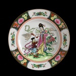 Prato em fina porcelana de origem Oriental, decorado com figuras femininas e ladeado por faixa com arranjos florais e frutos intercalados. Exemplar de coleção e em excelente estado. Dimensões: 26 cm.