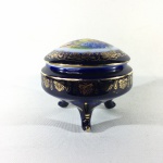 Delicado e luxuoso porta-joias em  fina porcelana azul cobalto apoiado por três pés, decorado com cena galante na tampa e guirlandas gravadas à Ouro 22k. Dimensões: 9 cm altura x 10 cm diâmetro.