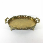 Antiga "BANDEJA" em metal dourado, formato oval, rematada com galeria vazada, alças volutadas e apoiada por 4 pés curtos. Presença de sinais do tempo. Dimensões: 23 cm x 14 cm x 4,5 cm.