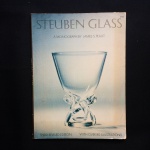 STEUBEM GLASS - A monograph by James S. Plaut. 3º edição. Livro com 111 páginas e 80 ilustrações. A Steuben Glass Works foi uma fabricante americana de vidros de arte, fundada no verão de 1903 por Frederick Carder e Thomas G. Hawkes em Corning, Nova York, que fica no condado de Steuben, de onde derivou o nome da empresa.