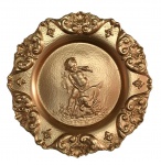 Antigo medalhão em pewter, estilo "Rococó" revestido de dourado, decorado com figura de "MENINO CAÇADOR E CÃO" ladeados por volutas, folhas de acanto e conchas. Pequeno rachado na borda. Exemplar raro e em excelente estado. Dimensões: 22 cm x 2 cm.