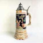 WESTERN GERMANY  ALT-GRENZAU 1894 - Antigo Tankard de coleção em cerâmica  policromada e esmaltada, decorado com  cena tradicional Alemã, querubins  com trombetas na parte inferior e estilizados. Tampa em metal cinzelado decorado com arabescos incustados. Dimensões: 28 cm altura.