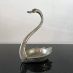 Elegante cisne em metal cinzelado e niquelado. Finíssimo acabamento. Exemplar em excelente estado. Dimensões: 15,5 cm x 8 cm x 11,5 cm.