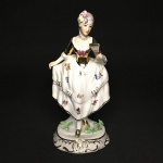 Bela estatueta "DAMA" em porcelana esmaltada e policromada. Peça numerada  121 / 2.  Presença de restauro imperceptível na mão. Dimensões: 18 cm x 7 cm x  8 cm.