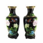 Imponente e antigo par de vasos Cloisonné, de origem Oriental, rematados com borboletas e arranjos Florais nas cores branco e azul sobre fundo preto. Exemplar de coleção e em excelente estado. Dimensões: 35 cm x 15 cm. A técnica cloisonné é de origem bizantina e foi introduzida na China no século XIV / Dinastia Ming. Sobre um objeto fabricado em metal, geralmente em cobre, aplicava-se um conjunto de finos fios dourados formando os contornos dos motivos desejados. Os favos, ou ""cloisons"", eram depois preenchidos com esmaltes coloridos, fortemente comprimidos e polidos até atingirem o acabamento desejado.