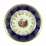 Belo prato de coleção em fina porcelana, estilo neoclássico,  decorado com Cena Greco-romana by  Angelica Kauffman ao centro e ladeado por larga faixa azul royal ostentando ricos arabescos em Ouro 22k. Exemplar em excelente estado. Dimensões: 19,9 cm x 3,5 cm.