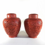 CHINA - Antigo e belo par de vasos em cobre revestido em laca na cor vermelho, decorados com cenas de nativos orientais, ladeado por arabescos . Apresenta marcas do tempo e tampa fixada. Dimensões: 22 cm altura x 17 diâmetro.