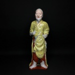 CHINA - Antiga escultura figurativa de Oriental em porcelana esmaltada em trajes típicos de cor predominante amarelo. Assinado. Exemplar de coleção e em excelente estado. Dimensões: 25 cm altura.