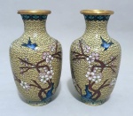 Belo e elegante  par de vasos Cloisonné decorado com flores e pássaros sobre fundo marfim. Exemplar parte de coleção. Dimensões: : 16 cm. A técnica do Cloisonné é de origem Bizantina e foi introduzida na China no século XIV / Dinastia Ming. Sobre um objeto fabricado em metal, geralmente em cobre, aplicava-se um conjunto de finos fios dourados formando os contornos dos motivos desejados. Os favos, ou ""cloisons"", eram depois preenchidos com esmaltes coloridos, fortemente comprimidos e polidos até atingirem o acabamento desejado.