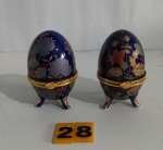 Par de porta Joia em porcelana ao gosto Fabergê no formato de Ovo com fundo azul e ricamente decorado com desenhos de florais, no centro circundado por metal dourado e sustentado por 3 pês arqueados em porcelana. Medindo 8 cm cada.