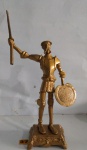 Dom Quixote em bloco de metal patinado dourado, medindo 44 cm de altura da base até a lança e 33 cm de altura da base ao Dom Quixote.