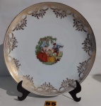 Prato decorativo em porcelana SCHMIDT (Made in Brazil), decorado com cena galante em reserva e frisos dourados e guirlandas. Diâmetro 25 cm.