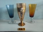 Conjunto de 03 taças  de coleção sendo uma dourada, azul e âmbar, medindo 17 cm.