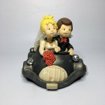 Casal de noivos no carro feito com massa de biscuit. Presença de sinais do tempo. Dimensões: 15 cm x 18 cm x 17 cm.