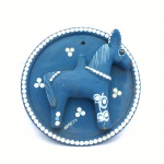 Placa circular em barro cozido em tons de azul decorado com animal ao centro e detalhes florais em branco. Exemplar com pequenas marcas do tempo. Dimensões: 22 cm x 5 cm,