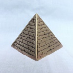 Antiga pirâmide em bronze decorado com detalhes geométricos. Exemplar em excelente estado. Pequena mossa na parte superior. Dimensões: 6 cm x 6 cm x 6 cm.