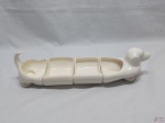 Jogo de 4 petisqueiras em porcelana na forma de cachorro basset. Medindo 42,5cm de comprimento total x 11cm de altura.