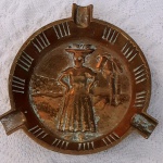CINZEIRO em BRONZE, decorado com coqueiro e mulher com cesto de frutas na cabeça. Diâmetro 11 cm