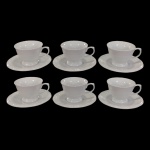 SCHMIDT - SEIS XÍCARAS DE CAFÉ EM PORCELANA SCHMIDT NA COR BRANCA, COM BORDAS EM DETALHES EM ARABESCO EM ALTO RELEVO NA MESMA COR.
