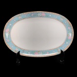 SCHMIDT - VOYAGE BARROCO - TRAVESSA OVAL EM PORCELANA SCHMIDT NA COR BRANCA, BORDA COM FAIXA AZUL COM DECORAÇÃO FLORAL EM VASOS E SALPICADAS, NAS CORES ROSA, BRANCA E VERDE, FAIXA INFERIOR COM DECORAÇÃO GEOMÉTRICA E FAIXA SUPERIOR FLORAL, LIGADAS POR CORRENTES COM DETALHES DOURADOS. - MED 3 X 33 X 21,5 CM.