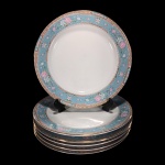 SCHMIDT - VOYAGE BARROCO - SEIS PRATOS PARA SOBREMESA EM PORCELANA SCHMIDT NA COR BRANCA, BORDA COM FAIXA AZUL COM DECORAÇÃO FLORAL EM VASOS E SALPICADAS, NAS CORES ROSA, BRANCA E VERDE, FAIXA INFERIOR COM DECORAÇÃO GEOMÉTRICA E FAIXA SUPERIOR FLORAL, LIGADAS POR CORRENTES COM DETALHES DOURADOS.