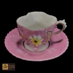 COLECIONISMO - XÍCARA PARA CAFÉ  COM  RESPECTIVO PIRES,  EM PORCELANA NAS CORES ROSA E BRANCA, DECORAÇÃO FLORAL EM ALTO RELEVO E SUSPENSA POR QUATRO PÉS.