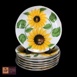  SETE PRATOS  PARA SOBREMESA EM PORCELANA NACIONAL NA COR BRANCA, PINTADA A MÃO, COM MOTIVOS DE GIRASSÓIS  E PEGAS E FRISOS DOURADOS ASSINADOS. ALGUNS APRESENTAM PERDA NA PINTURA - MED:18,5 CM.