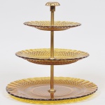 Prato para doces de 03 estágios, pratos em vidro ambar lapidado em losangos e raias e coluna central em material sintético patinado a ouro. Med: 30cm