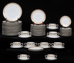 Parte de serviço de jantar em porcelana real no tom branco decoração policromada com motivos florais nas bordas e aplicações a ouro composto por 17 pratos rasos, 15 pratos de sobremesa, 12 pratos para pão e 09 consomês com pires