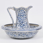 LUIZ SALVADOR - Gomil com bacia em cerâmica esmaltada e vitrificada, decorada no tom azul com flores e folhas. bojo gomado e bordas peroladas. Peça marcada. Med: 28cm de altura (Gomil) e  41 x 15cm (Bacia) Desgastes do tempo