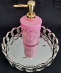 Bandeja espelhada com argolas em metal entrelaçadas, e dispenser de sabonete líquido em vidro rosa com Pump em plástico dourado estampa floral. Diâmetro:  22 e altura: 4,5 cm e  Atura: 18 cm( dispenser)- Bandeja com uma mancha.