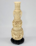Vaso oriental em marfinite, decorado com relevos de animais e alças no formato de cabeça de elefantes. Medida total 33 cm.